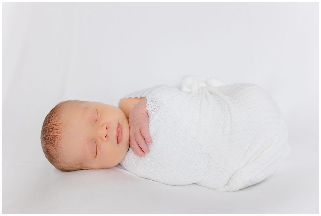 Individual photo of newborn wrapped in white swaddle